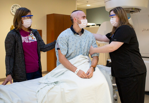 Two providers help a patient get ready for treatment