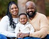 Arlene Brown poses outside with her husband and baby