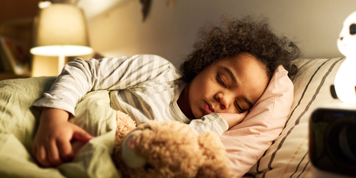 A young girl sleep in bed while holding a stuffed animal