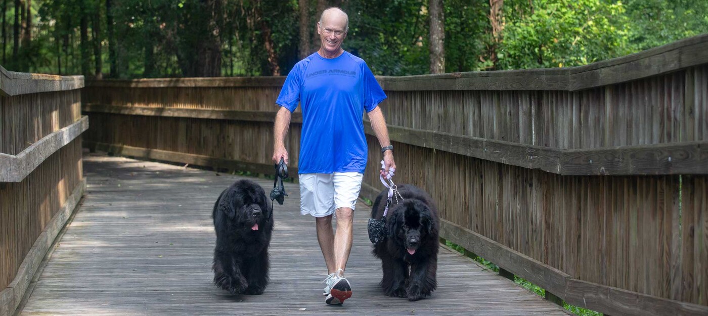 Kerry May walks with his Newfoundlands, Sirius and Mavis, in Raleigh, NC. Kerry May walks with two large, black dogs on leashes.