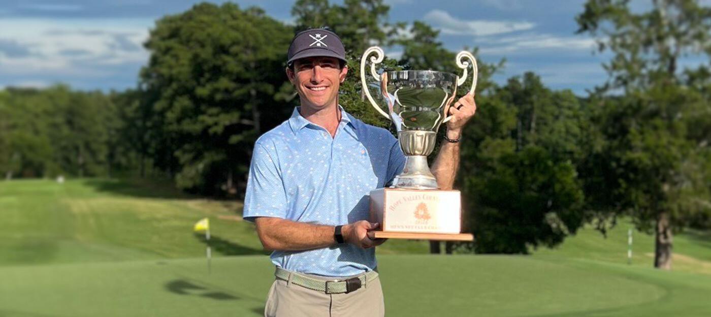 Taylor Donner holds up a trophy after winning his golf club's championship. Photo courtesy of Taylor Donner. A man stands on a golf course, smiling, while holding up a trophy