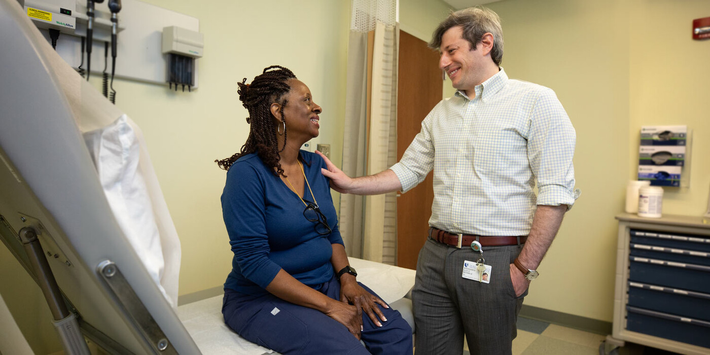 Alex Michaels, MD, a hernia surgeon at Duke, consults with a patient. A provider speaks with a patient in an exam room