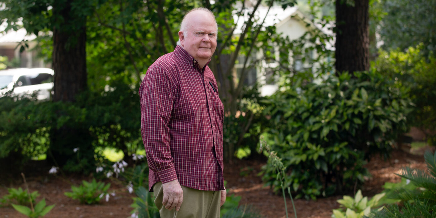 David Phillips stands outside of his North Carolina home. David Phillips stands in front of some trees and other vegetation