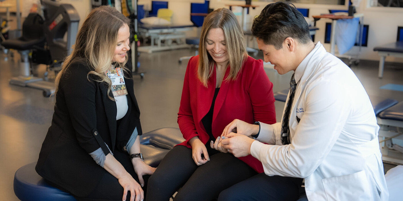 Occupational therapist Theresa Hallenen and orthopaedic and peripheral nerve surgeon Neill Li, MD, examine Jessi Wood's hand during an occupational therapy session.. Occupational therapist Theresa Hallenen and orthopaedic and peripheral nerve surgeon Neill Li examine Jessi Wood's hand during an occupational therapy session..