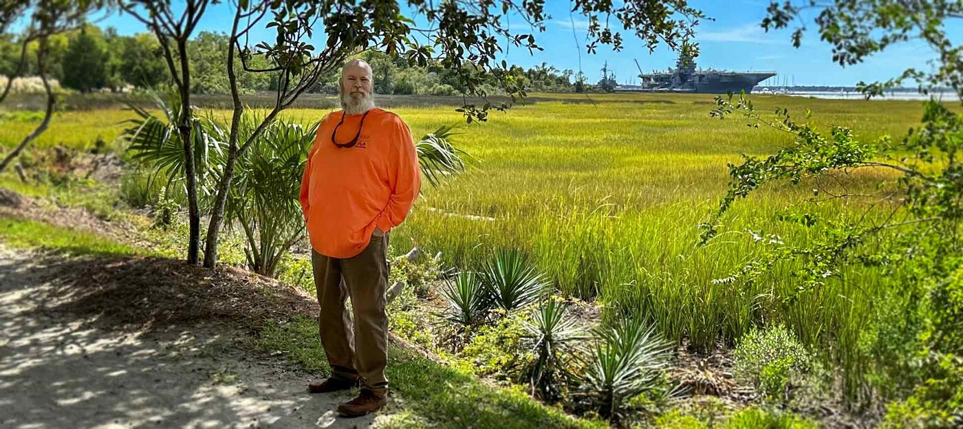 John White stands on a trail at Charleston Harbor in Mt. Pleasant, SC. Photo courtesy of Cindy White John White stands on a path with a marsh and a boat in the background