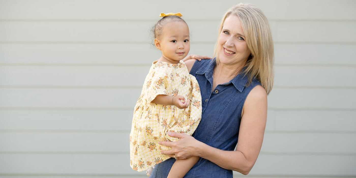 Darla Harvey holds Kara Pace in Wake Forest, NC. Harvey donated a portion of her liver to Kara in 2023. Darla holds Kara outside in front of the wall of a home