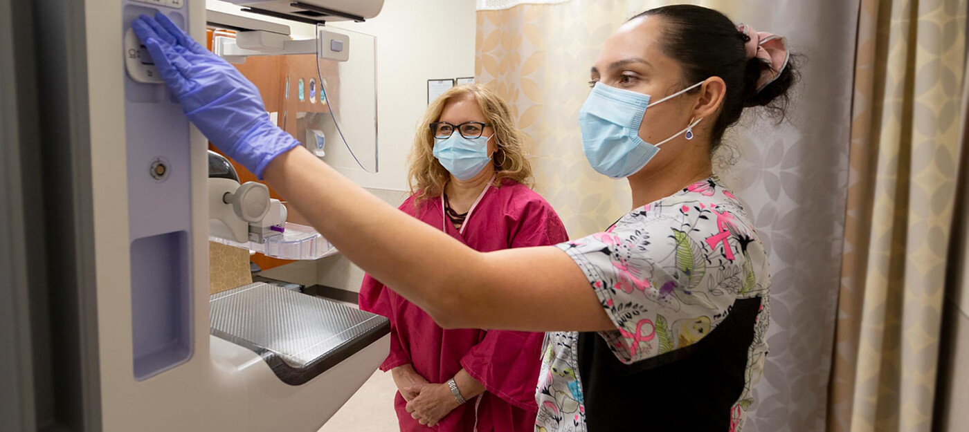 A provider helps a patient get ready for a mammogram