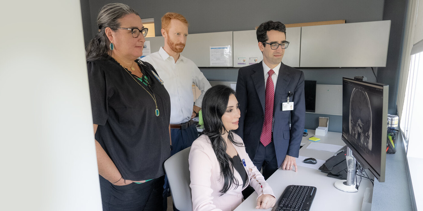 From left, Denise Lally-Goss, ANP; Patrick Codd, MD; Leena Shahla, MD; and Jordan Komisarow, MD, work together as part of Duke's pituitary tumor team. From left, Denise Lally-Goss, ANP, Patrick Codd, MD, Leena Shahla, MD, and Jordan Komisarow, MD look at a brain scan on a computer together.
