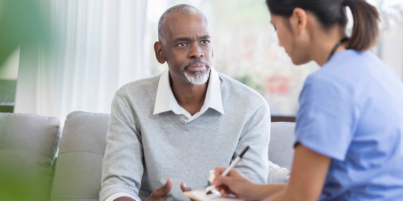 A man talks to a nurse as she takes notes