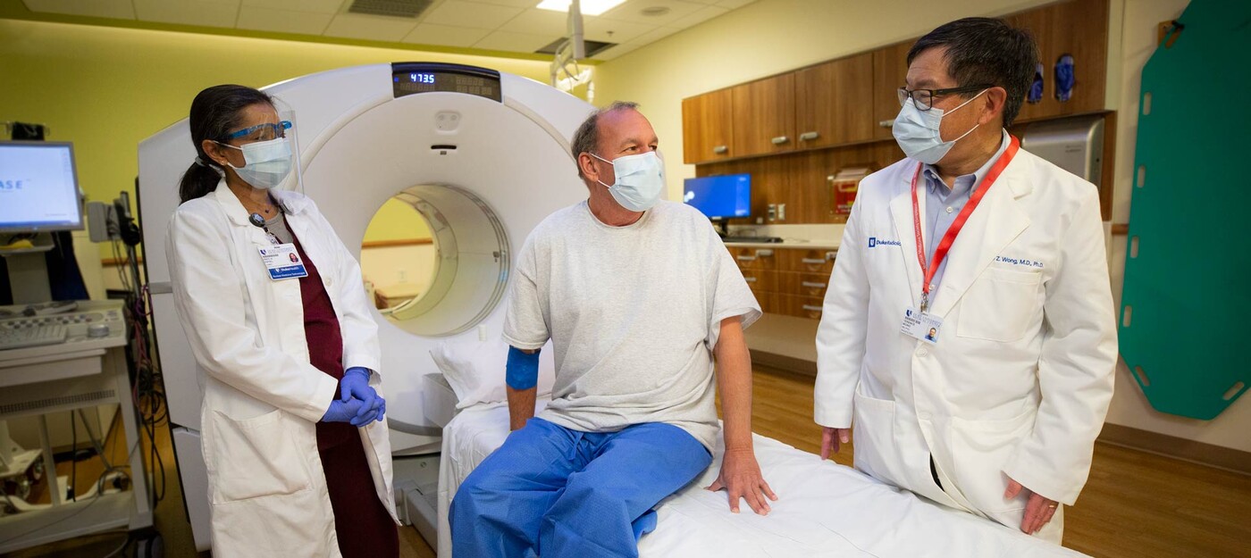 Priti Patel, CNMT, left, and Terence Wong, MD, PhD, right, meet with a patient before his PSMA PET/CT scan. Two providers meet with a patient before their (PSMA) PET/CT