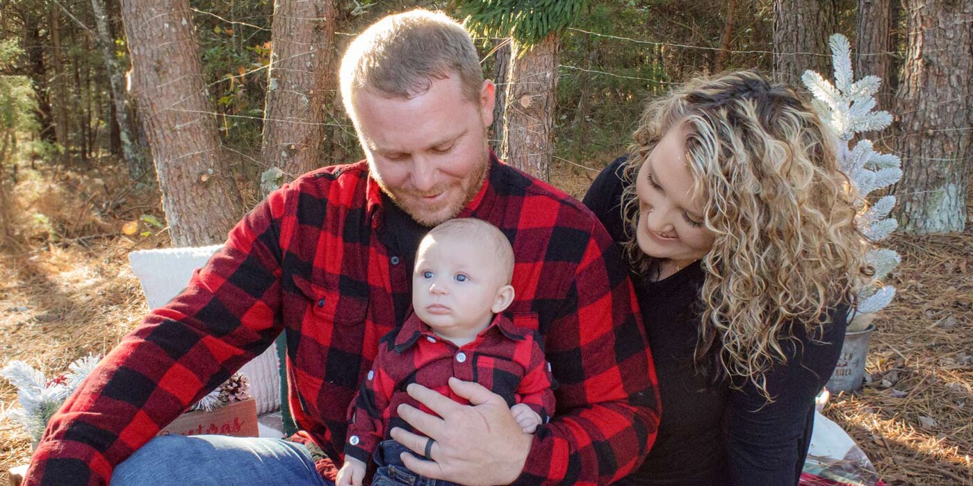 Tyler Wilfong shares a loving moment with his wife and baby boy. Photo courtesy of Haze Photography Man and wife look at baby boy