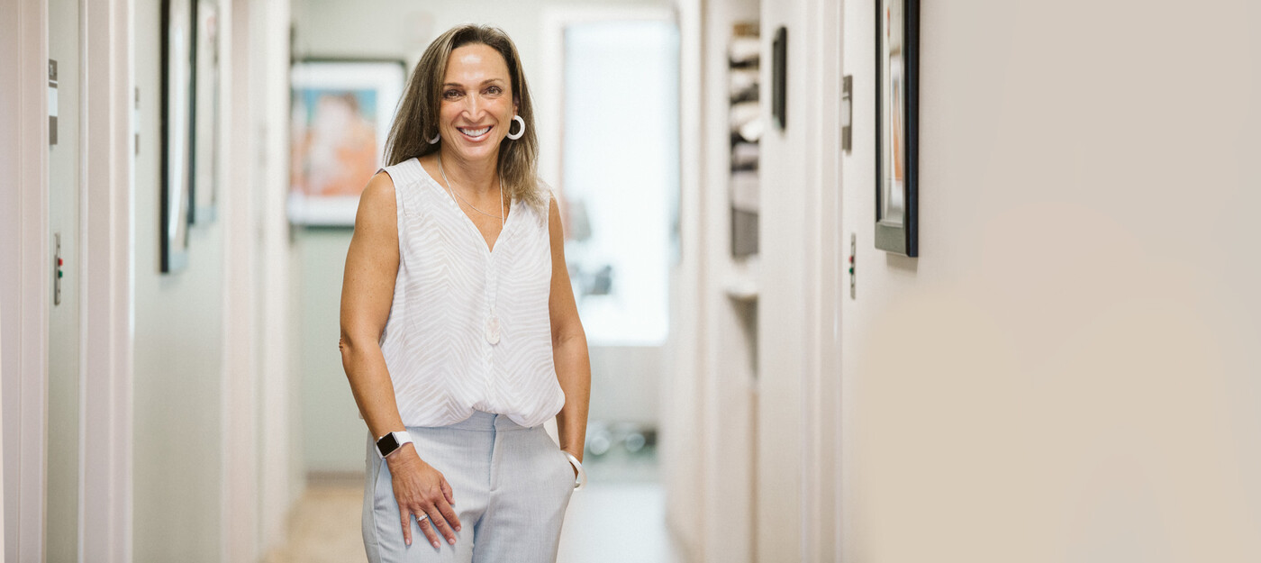 Susann Clifford, MD, offers treatments with the MonaLisa Touch® laser to help women with vaginal dryness. Dr. Clifford smiles inside the clinic hallway