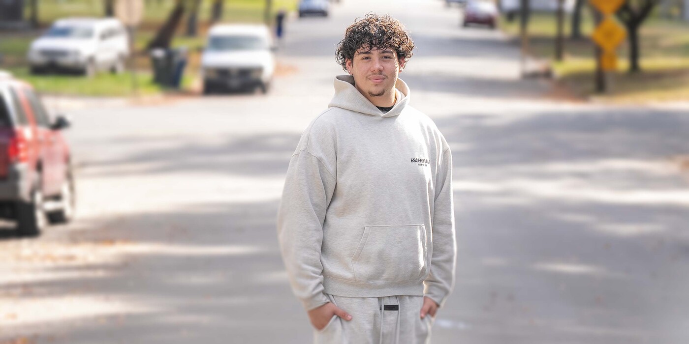 High school senior Fernando Morazán stands near his home in Durham, NC. Fernando stands on a street and smiles