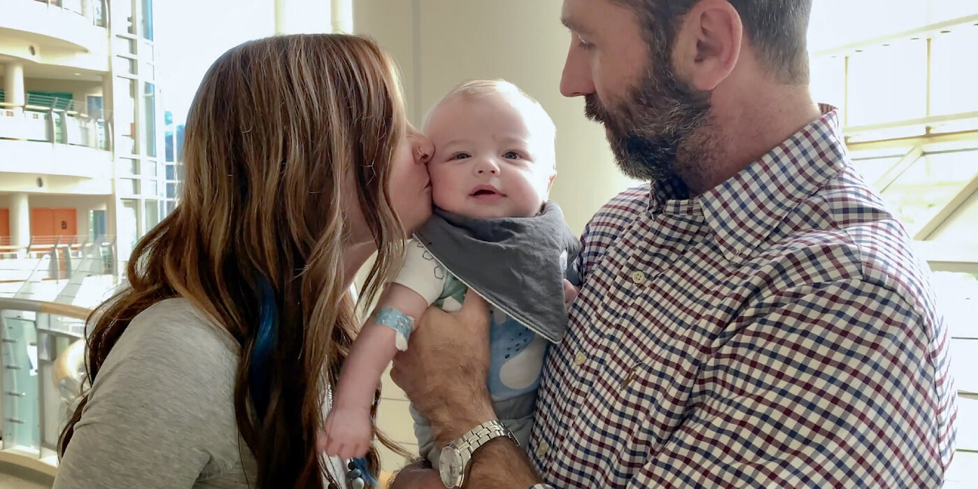 Asher Hobby, middle, with his parents at Duke Children’s Hospital. Drew Hobby holds his son Asher, while Asher's mother Kayle kisses Asher on the cheek.